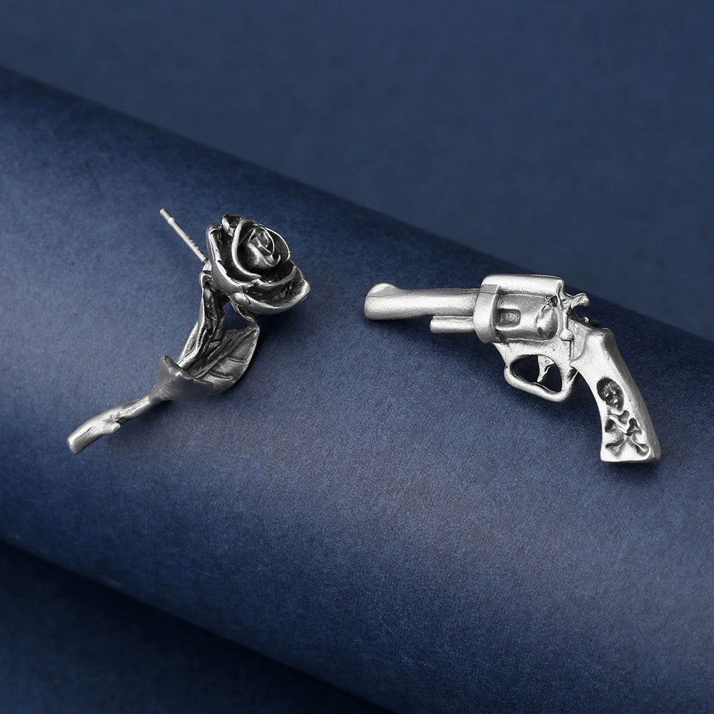 Niche storytelling rose and revolver shaped earrings