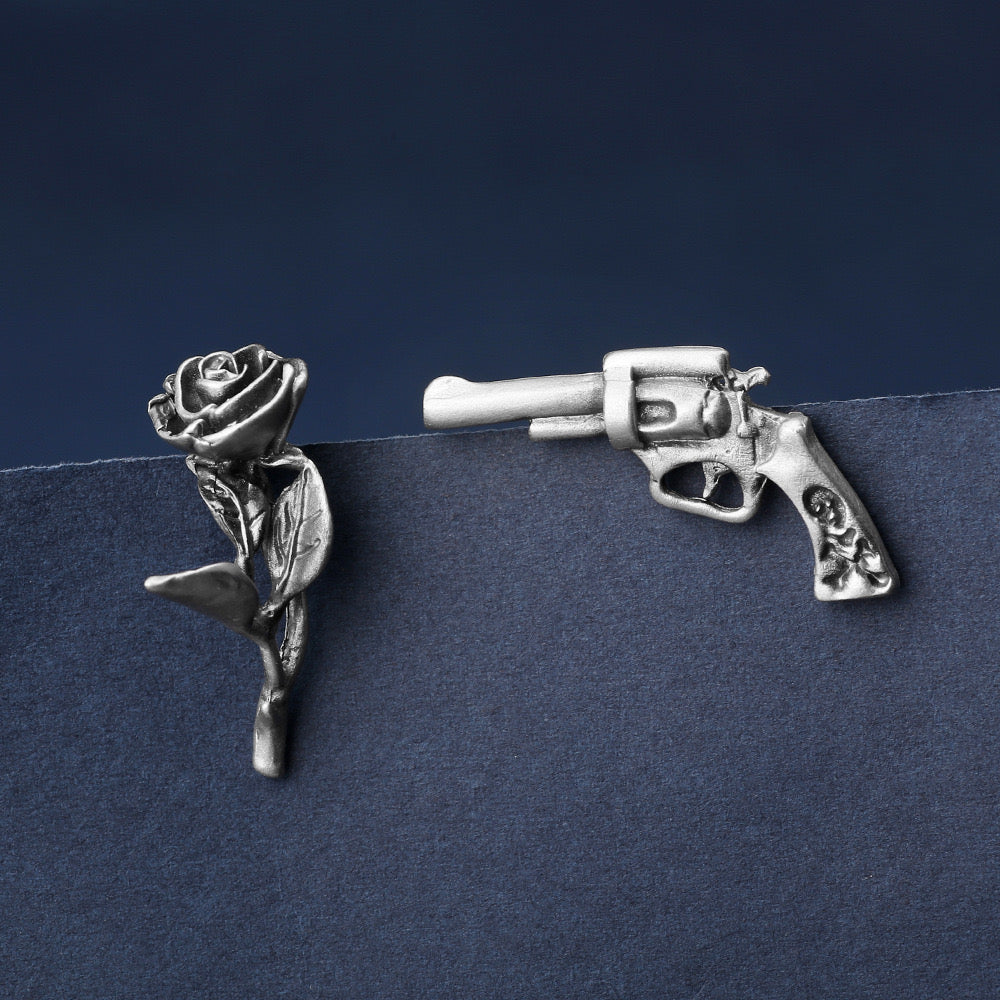 Niche storytelling rose and revolver shaped earrings